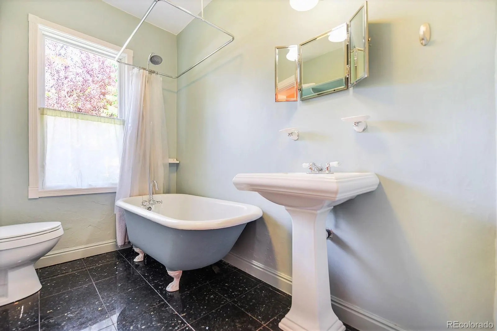 Bath with claw-foot tub and black marble floor