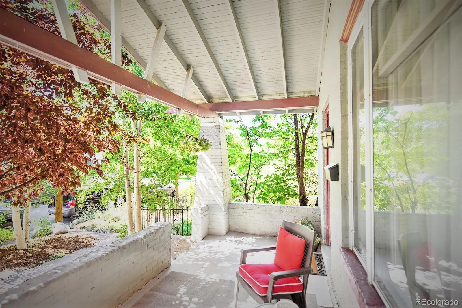 Shaded front porch with red chairs
