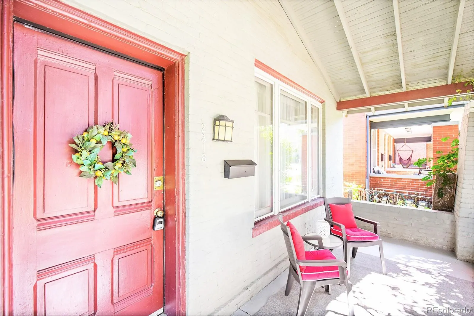 Red front door with wreath on the covered porch at 2318 North Ogden Street