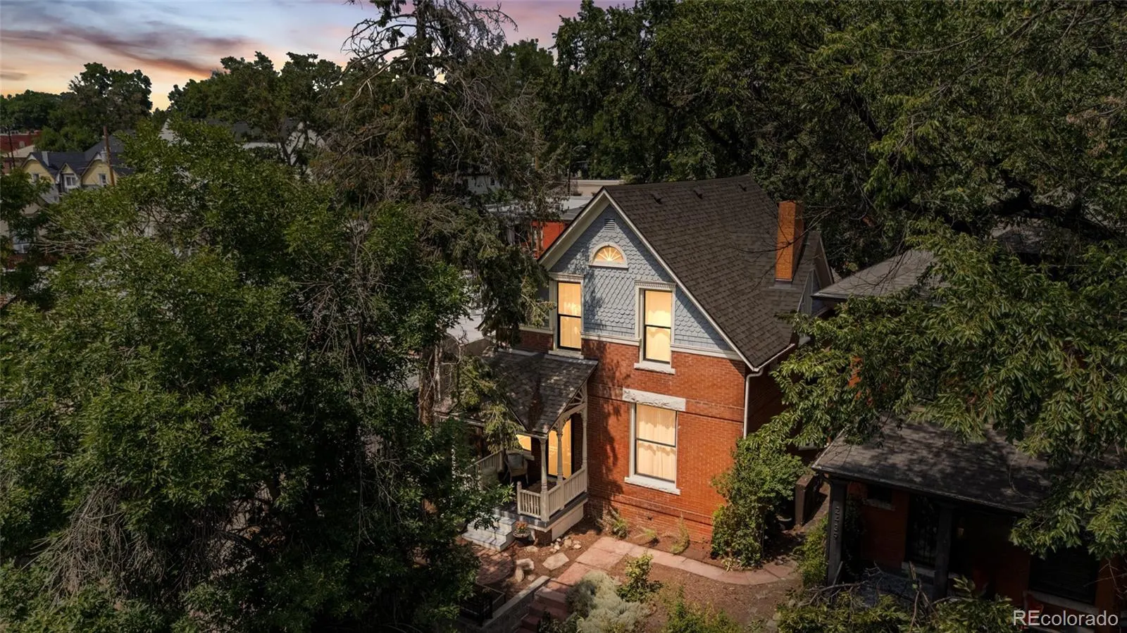 The 1894 brick Victorian at 2441 West Caithness Place at dusk beneath mature trees