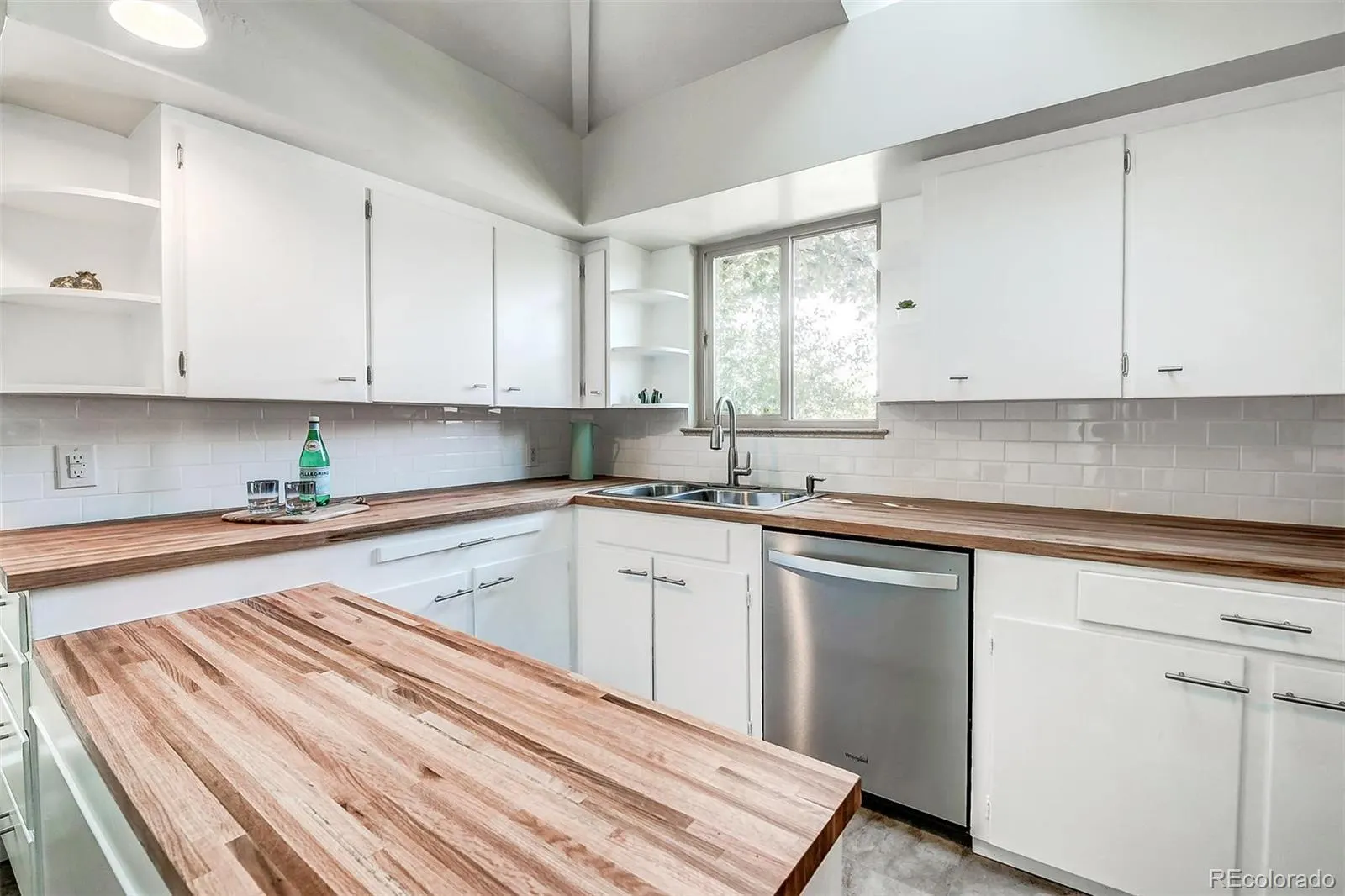 Kitchen with butcher-block island and white cabinets