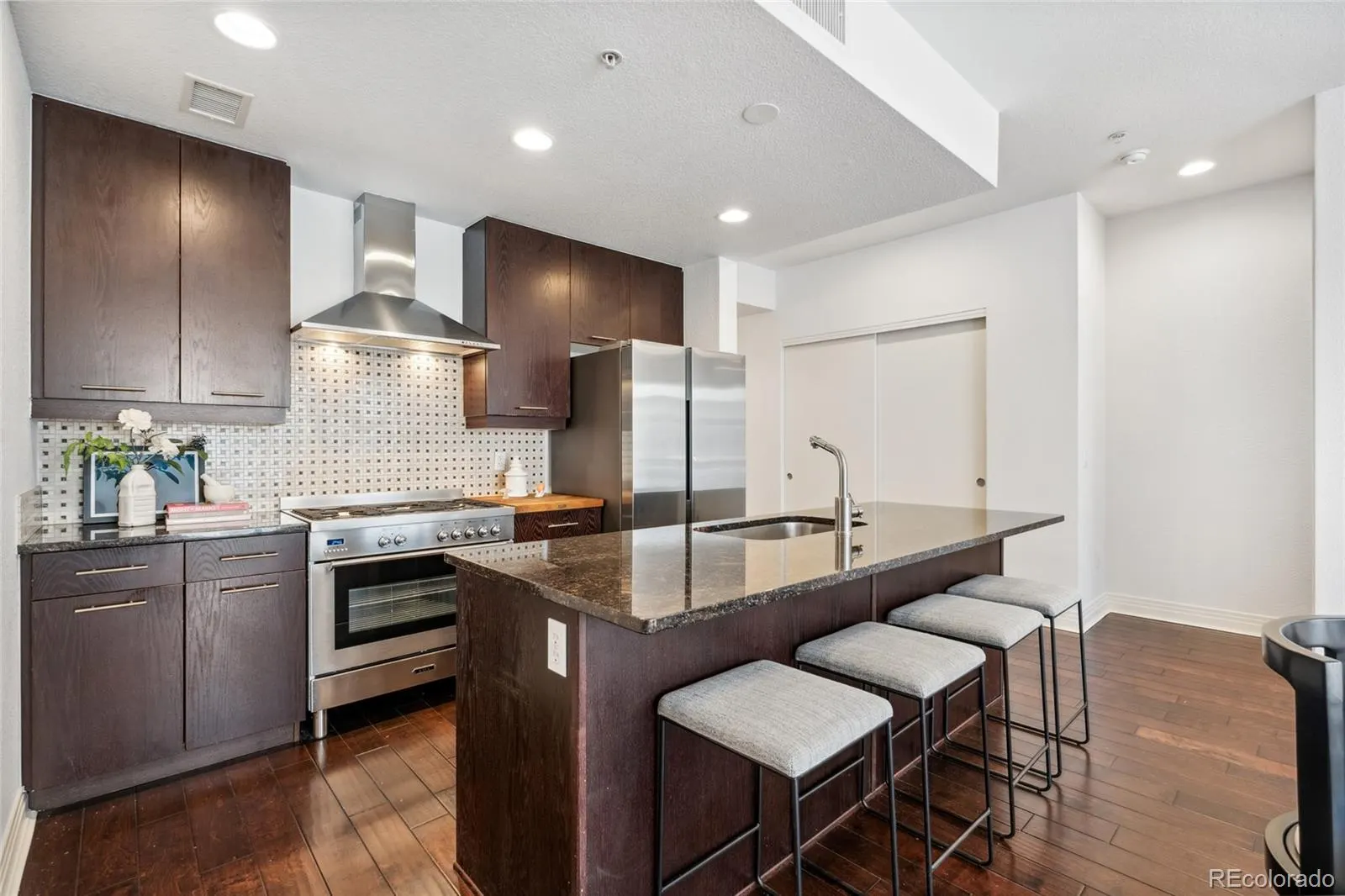 Kitchen with island, stone counters and dark cabinetry