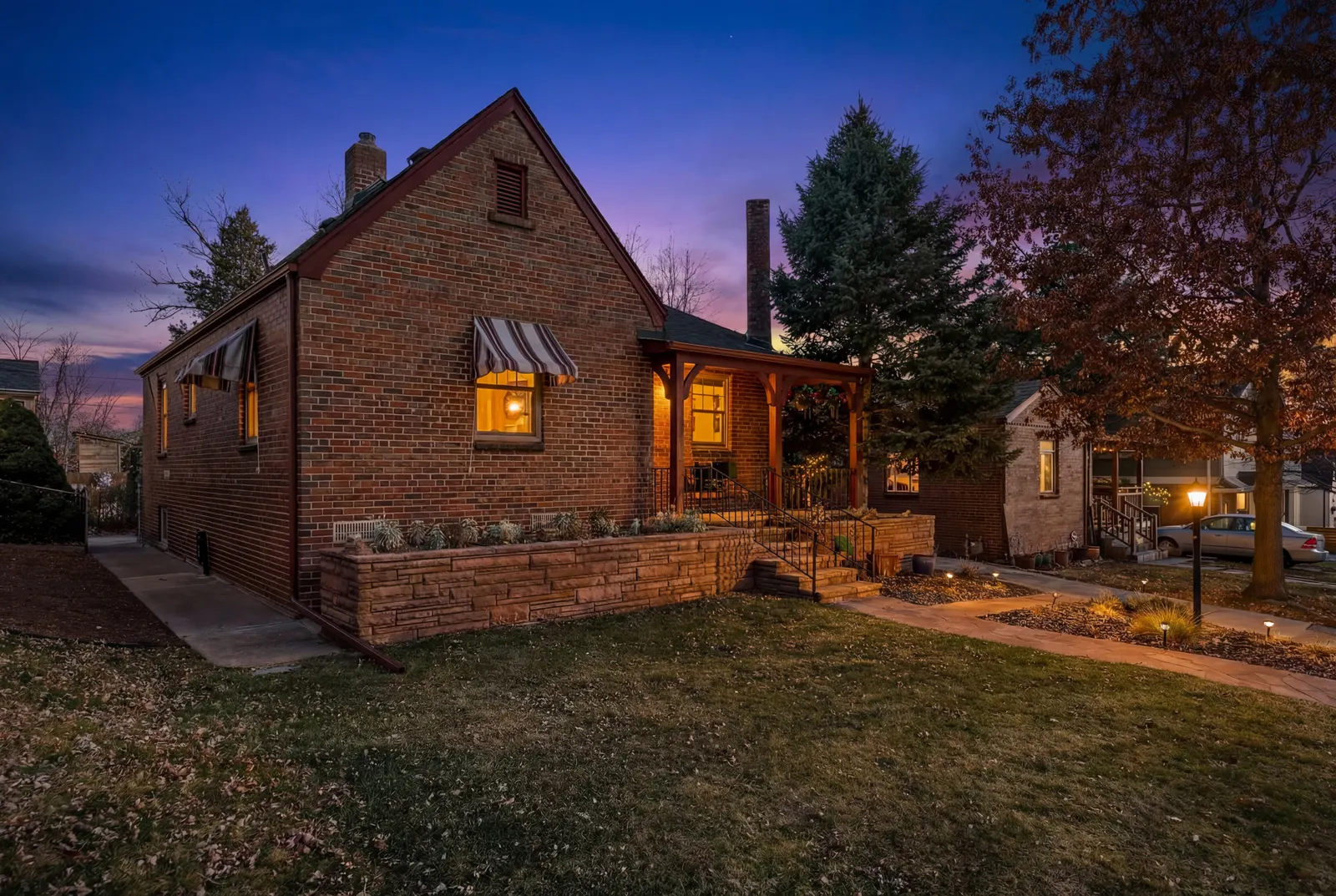 Brick Tudor at 2814 Stuart Street at twilight, windows lit, lawn and covered porch in front