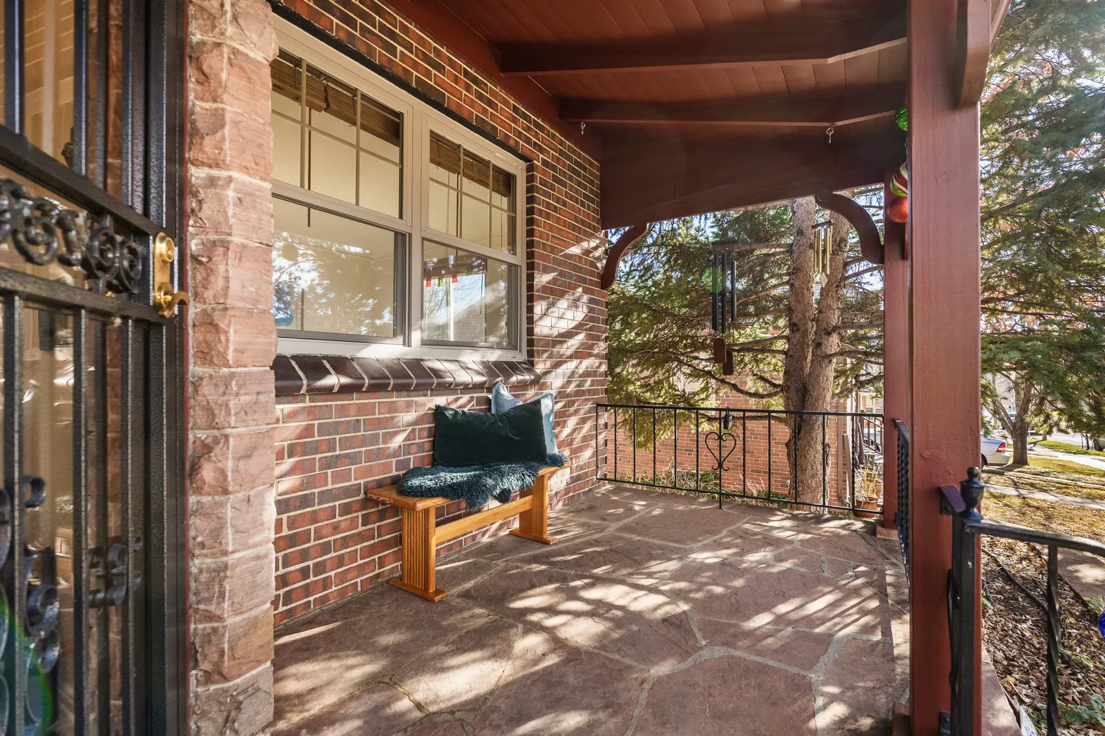 Bench on the covered front porch beside the brick façade