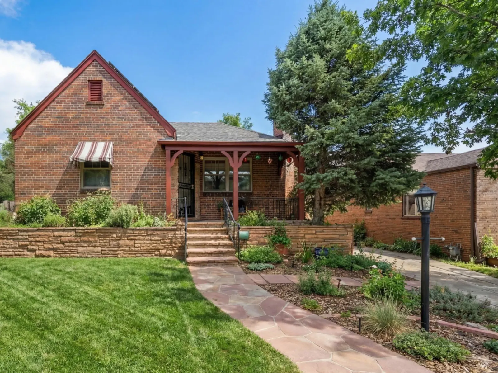 Front façade of the 1938 brick Tudor with its steep gable, covered porch and stone retaining wall