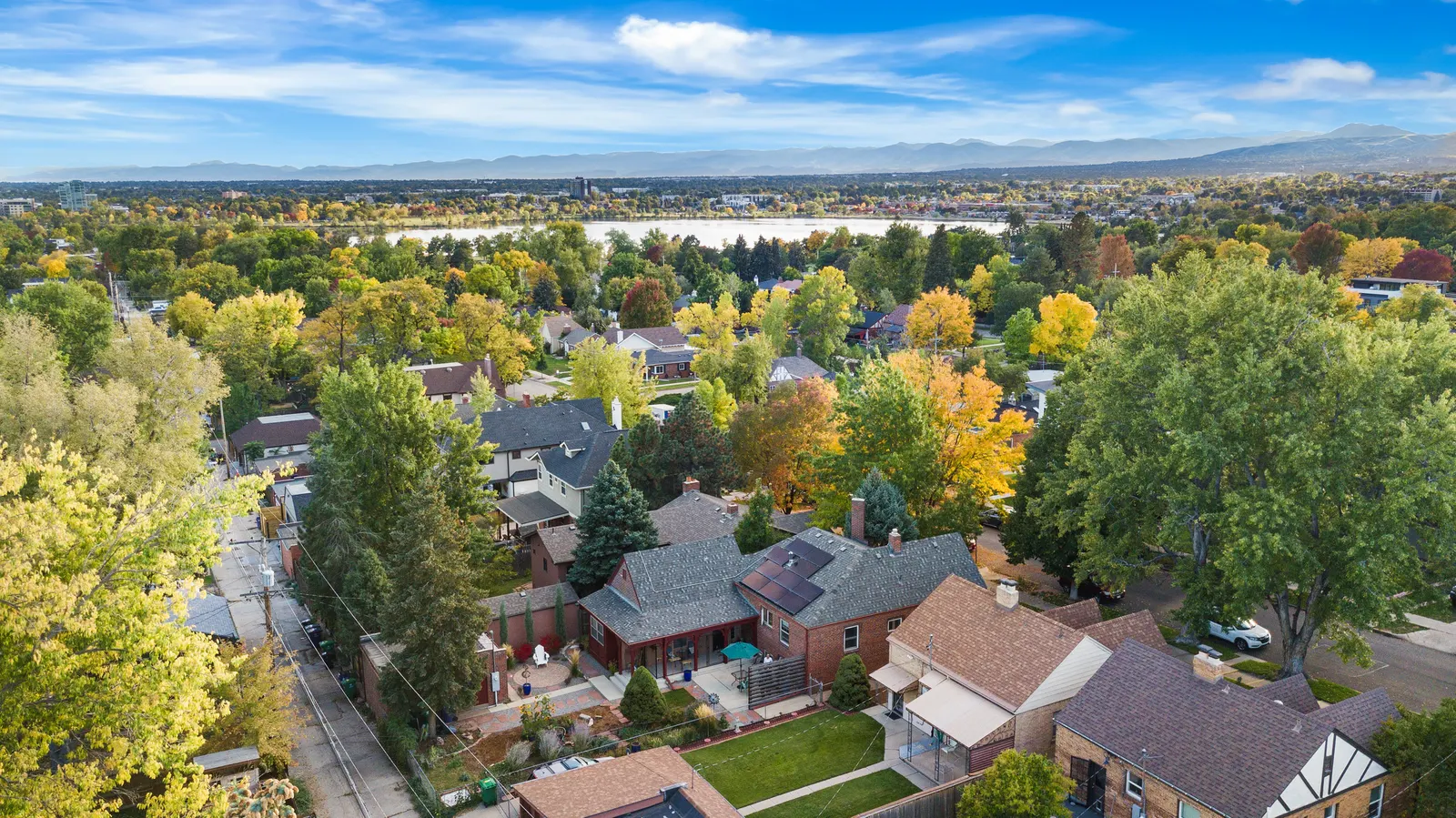 Aerial view over Sloan’s Lake neighborhood rooftops toward the lake and the Front Range