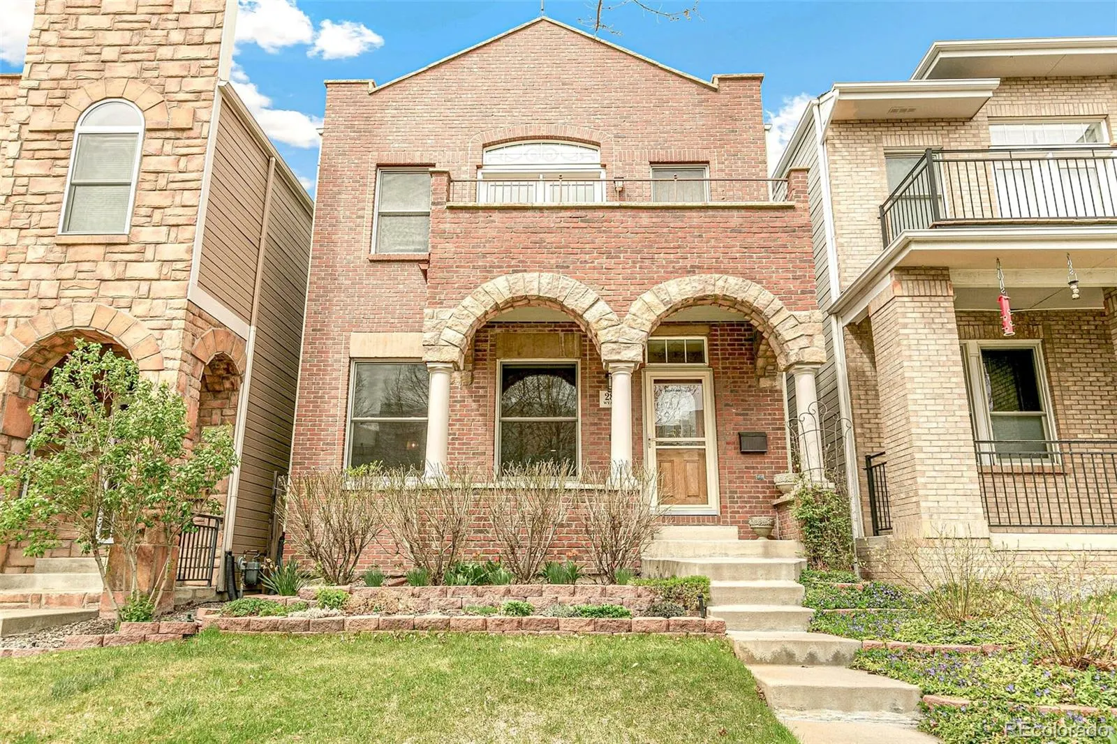 Brick and stucco front of 2821 Wyandot Street with arched porch and balcony