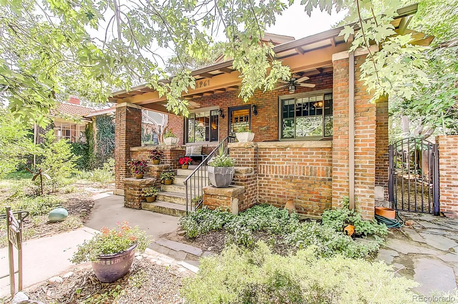 The 1912 Craftsman bungalow at 4261 Federal Boulevard behind mature trees