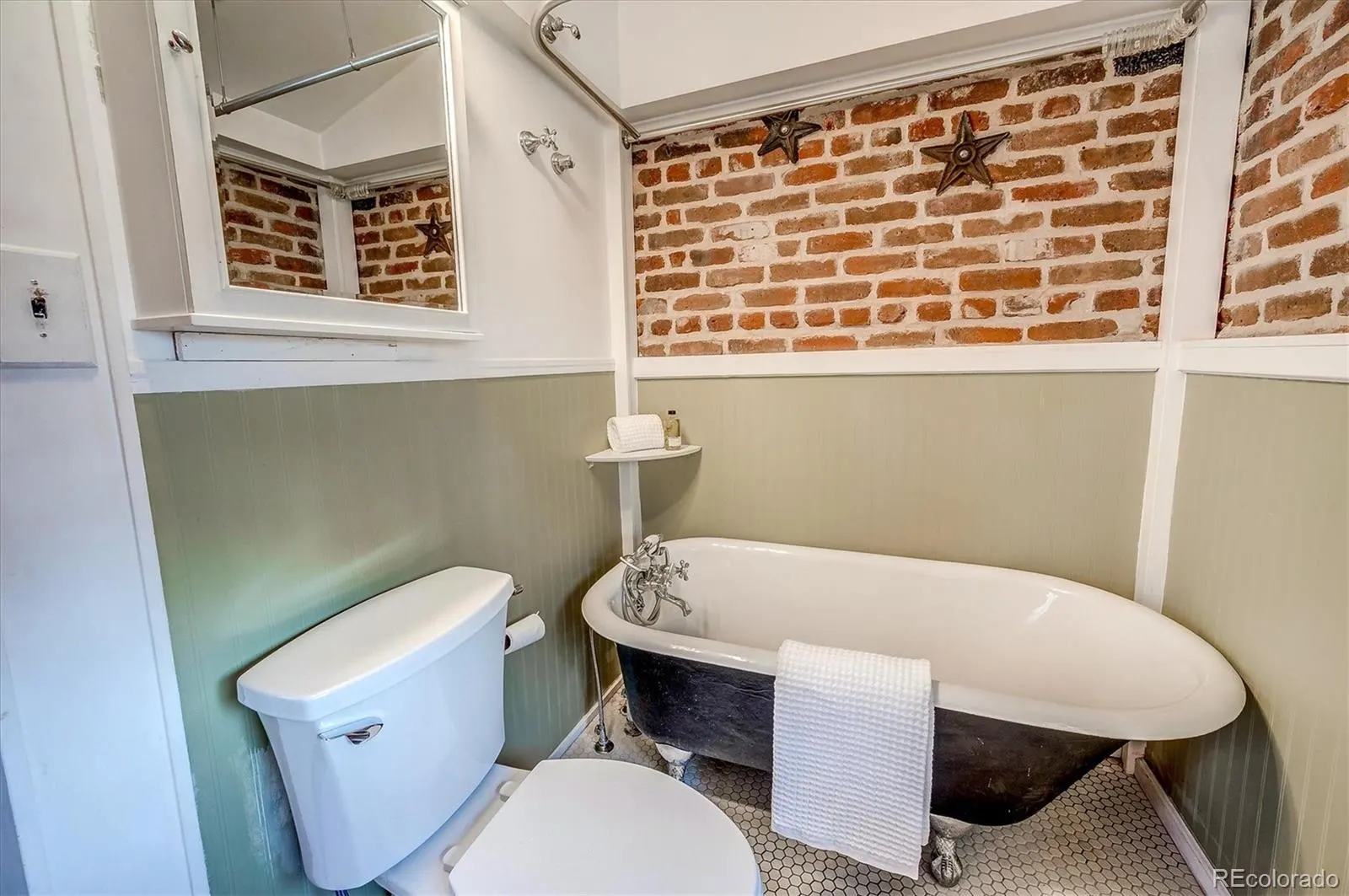 Claw-foot tub beneath exposed brick