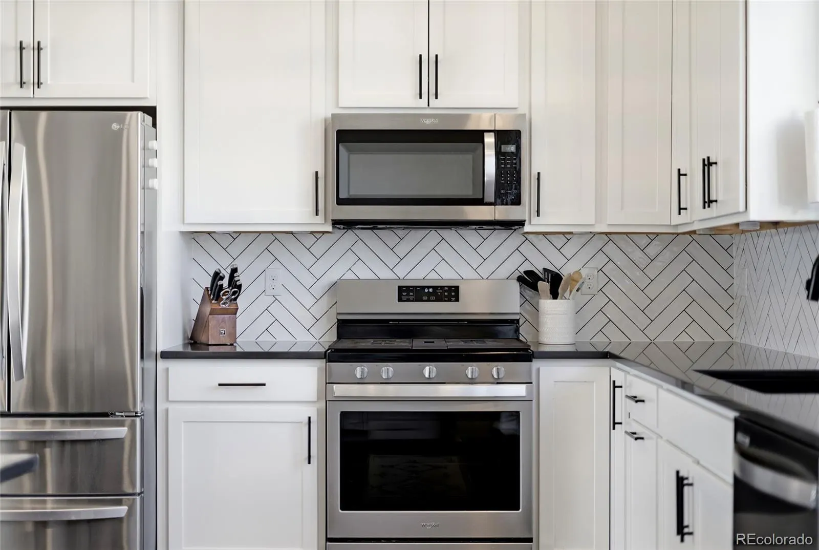 White kitchen with herringbone backsplash and gas range